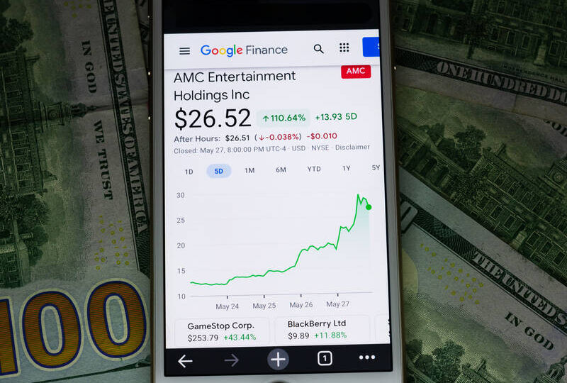 AMC Entertainment share price and graph showing recent stock rally on smartphone. 100 dollars bills background. - San Jose, California, USA - May 27, 2021