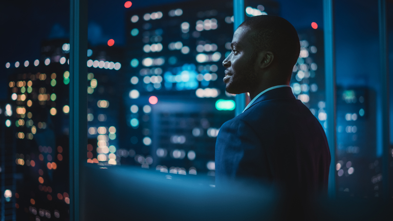 Successful Businessman Looking Out of the Window on Late Evening
